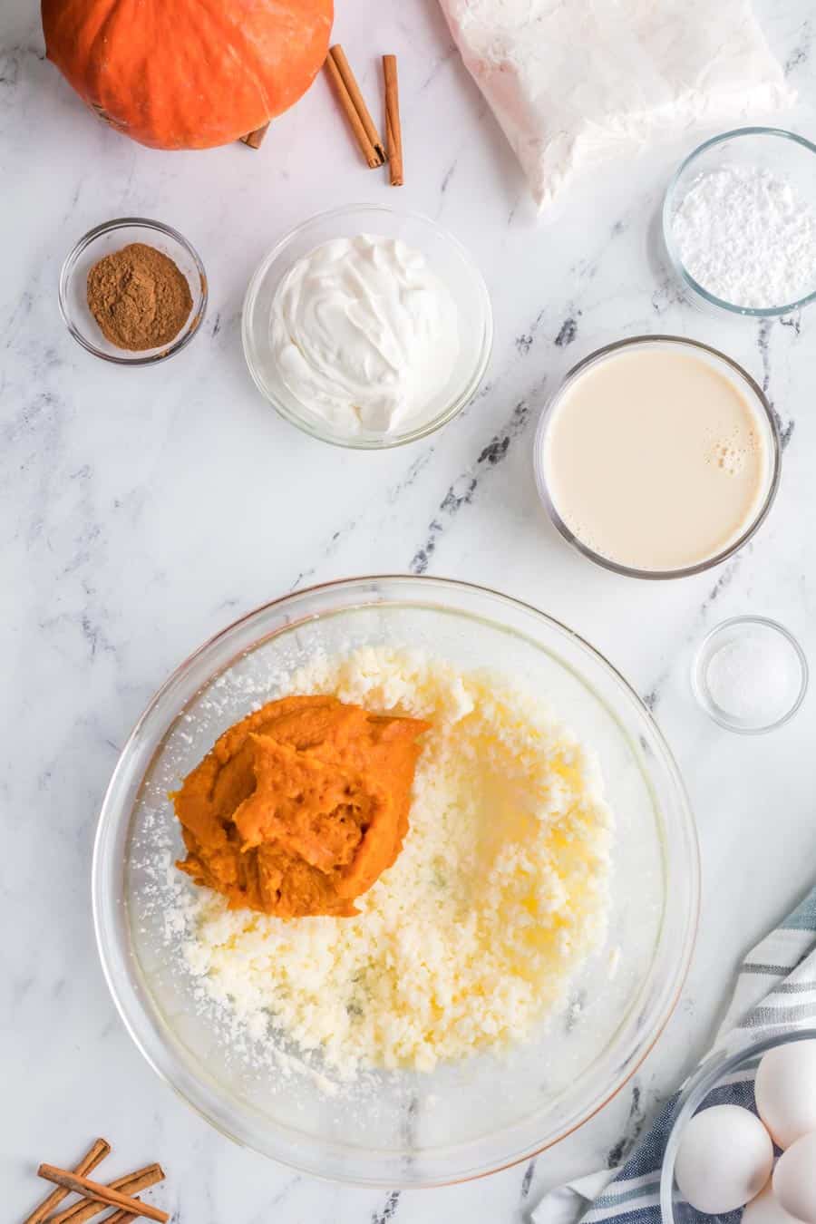 raw ingredients of the thick pumpkin cake in clear glass bowls on a marble table - the contrast of marble and sweet white ingredients and a deep orange pumpkin color
