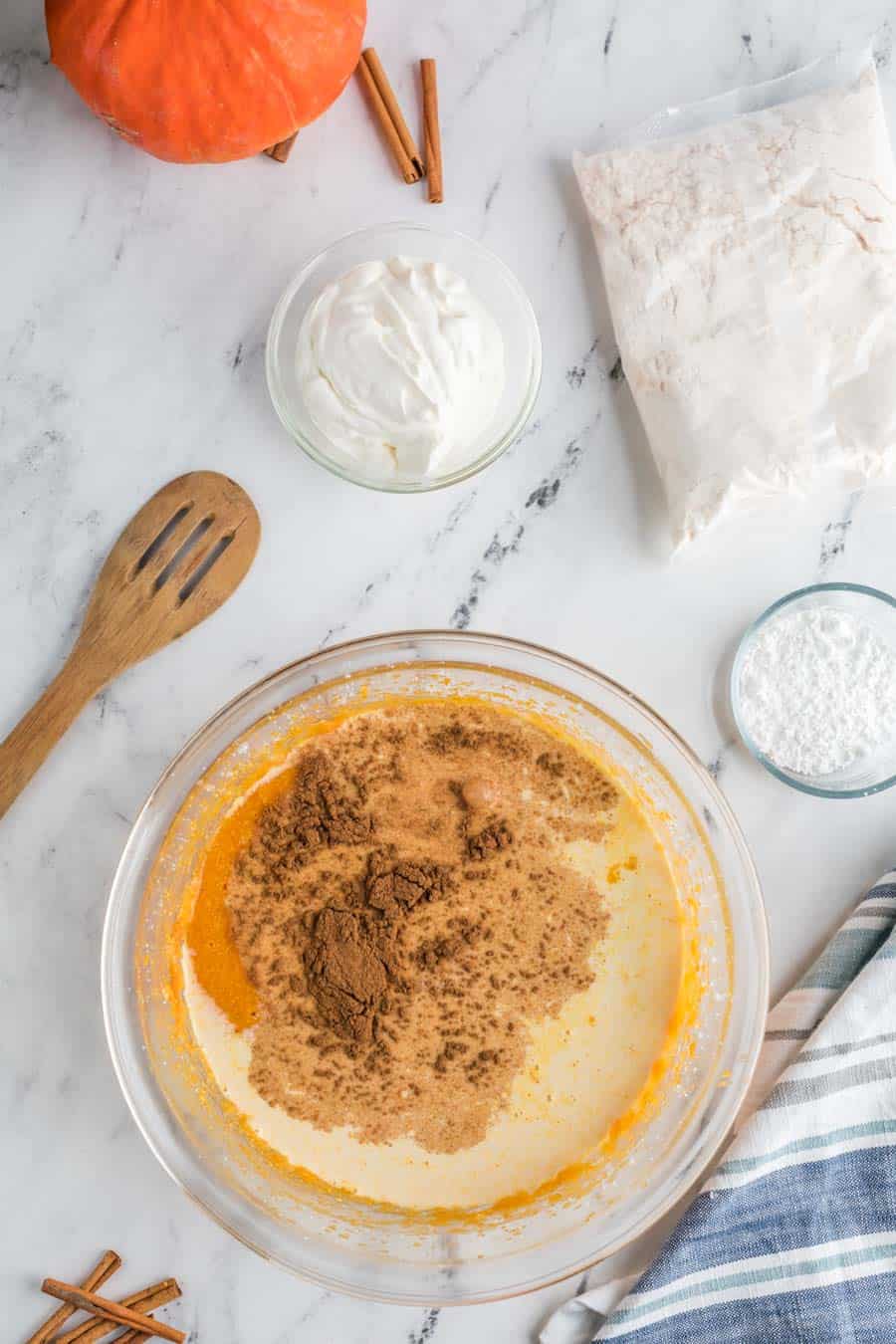 raw ingredients of the thick pumpkin cake in clear glass bowls on a marble table - the contrast of marble and sweet white ingredients and a deep orange pumpkin color