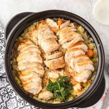 top view of rice and veggies in an instant pot with sliced chicken on top