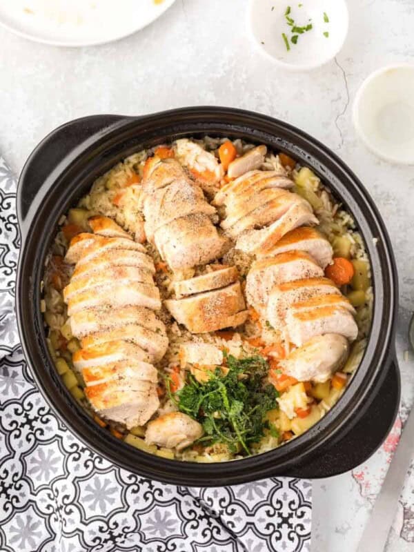 top view of rice and veggies in an instant pot with sliced chicken on top