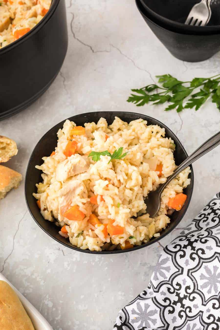 A black bowl of stovetop chicken and rice with a fork in it.