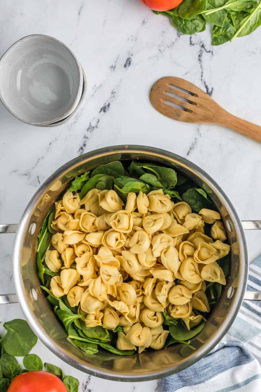 top view pot with tortellini laid over a bunch of lettuce