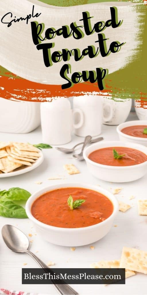 vertical pinterest pin of peppered orange tomato soup in white bowls garnished with basil and crackers basil and spoon laying to the side. Text reads: "simple roasted tomato soup"