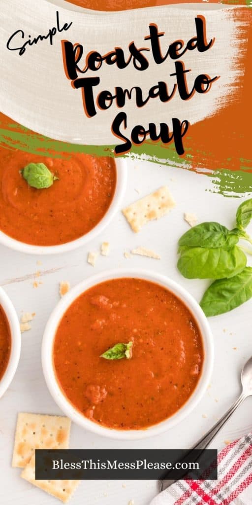 vertical pinterest pin, pictured: peppered orange tomato soup in white bowls garnished with fresh basil sprig cracked pepper with square salted crackers basil and spoon laying to the side. Text reads: "simple roasted tomato soup"