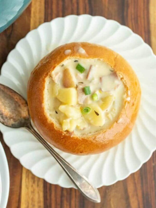 clam chowder in a bread bowl on a white plate