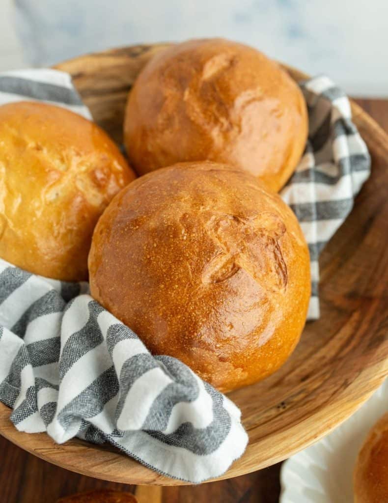 wooden bowl and three golden brown rolls