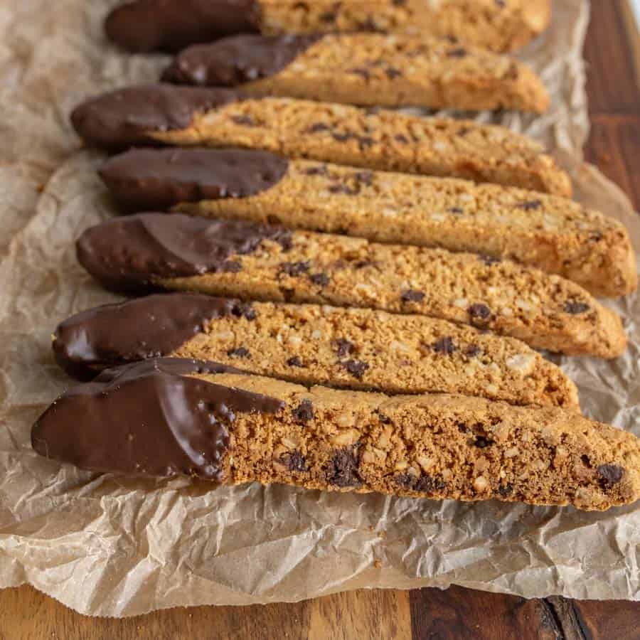 close up of biscotti on a parchment with chocolate chips and one end lightly covered in chocolate