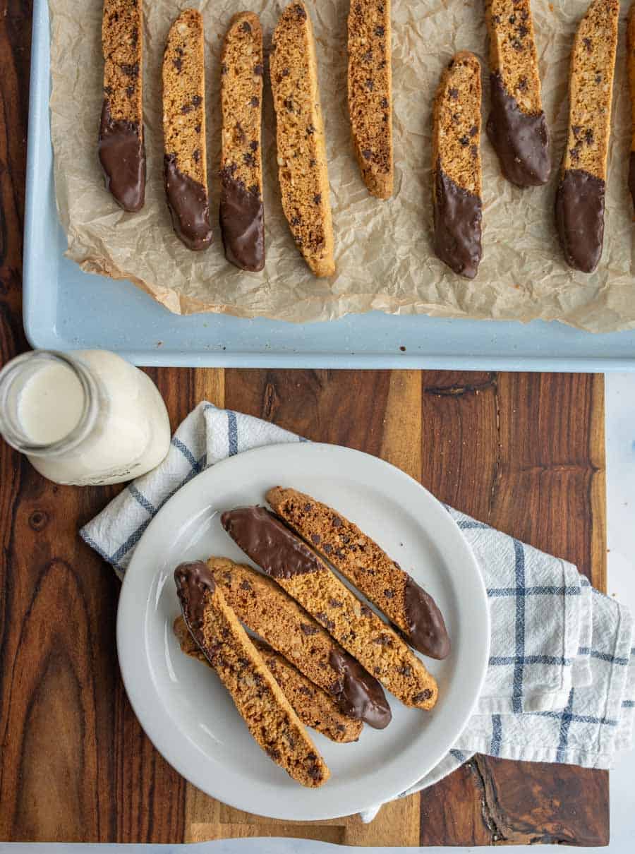 biscotti on a plate with chocolate chips and one end lightly covered in chocolate