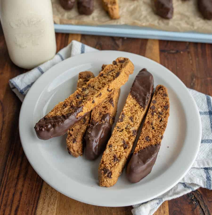 biscotti on a plate with chocolate chips and one end lightly covered in chocolate