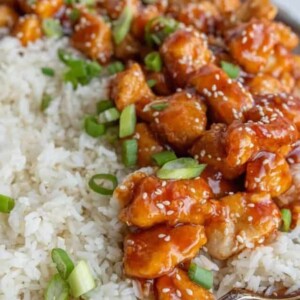a plate of sesame chicken with rice