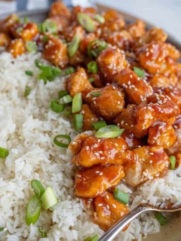 a plate of sesame chicken with rice