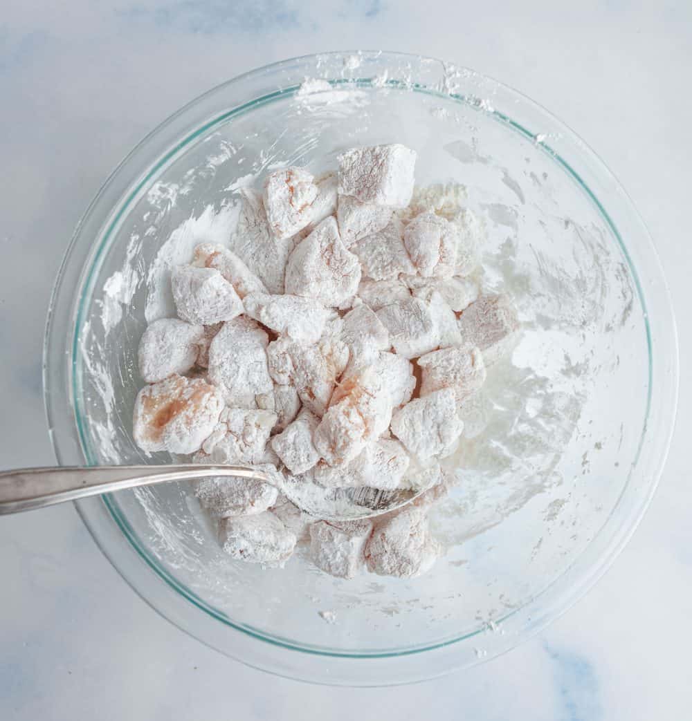 small raw chicken cubes dusted in flour in a large bowl.