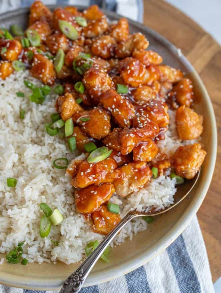 Delicious looking bowl of sesame chicken over steamed rice.