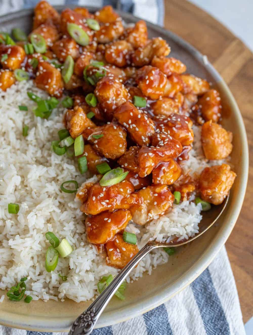 Delicious looking bowl of sesame chicken over steamed rice.