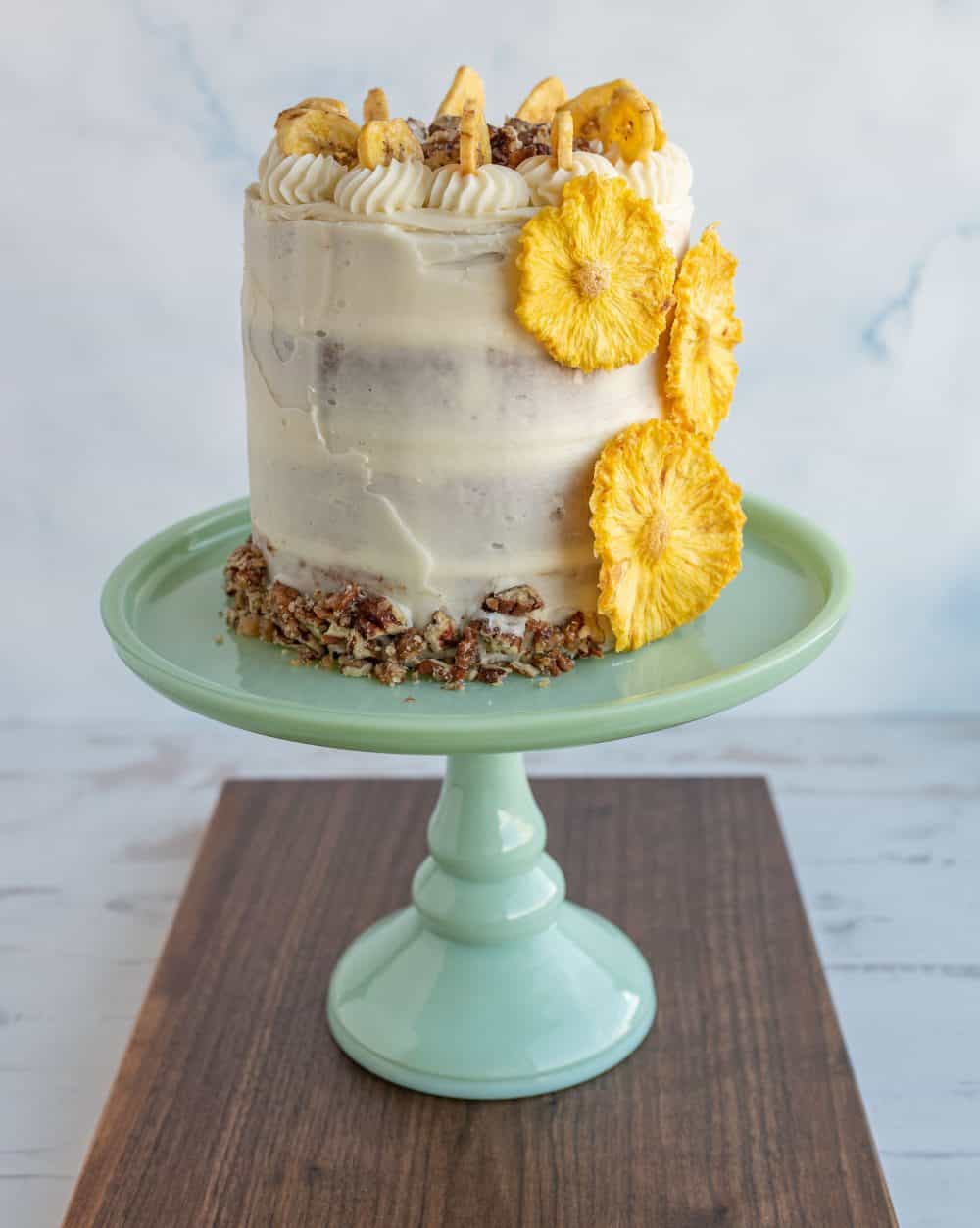 side view entire rustic frosted hummingbird cake on a teal stand.