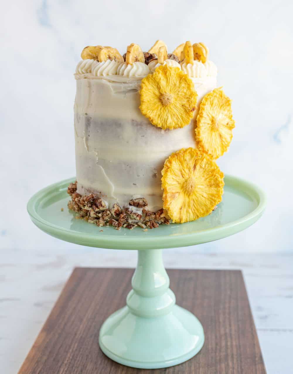 side view entire rustic frosted hummingbird cake on a teal stand.