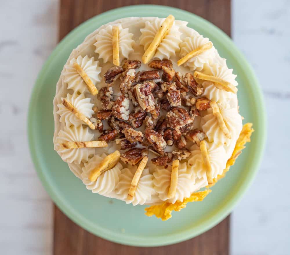 top view of hummingbird cake with banana chips and candied walnuts on top.