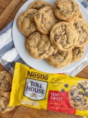 a plate stacked with chocolate chip cookies next to a bag of semi sweet chocolate morsels