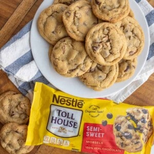 a plate stacked with chocolate chip cookies next to a bag of semi sweet chocolate morsels made from the original toll house cookie recipe.