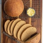 beautiful perfectly round baked bread loaf and then some slices that are buttered