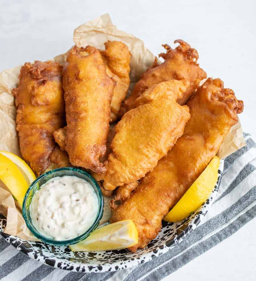 crispy golden deep fried and beer battered fish with tartar sauce and lemons