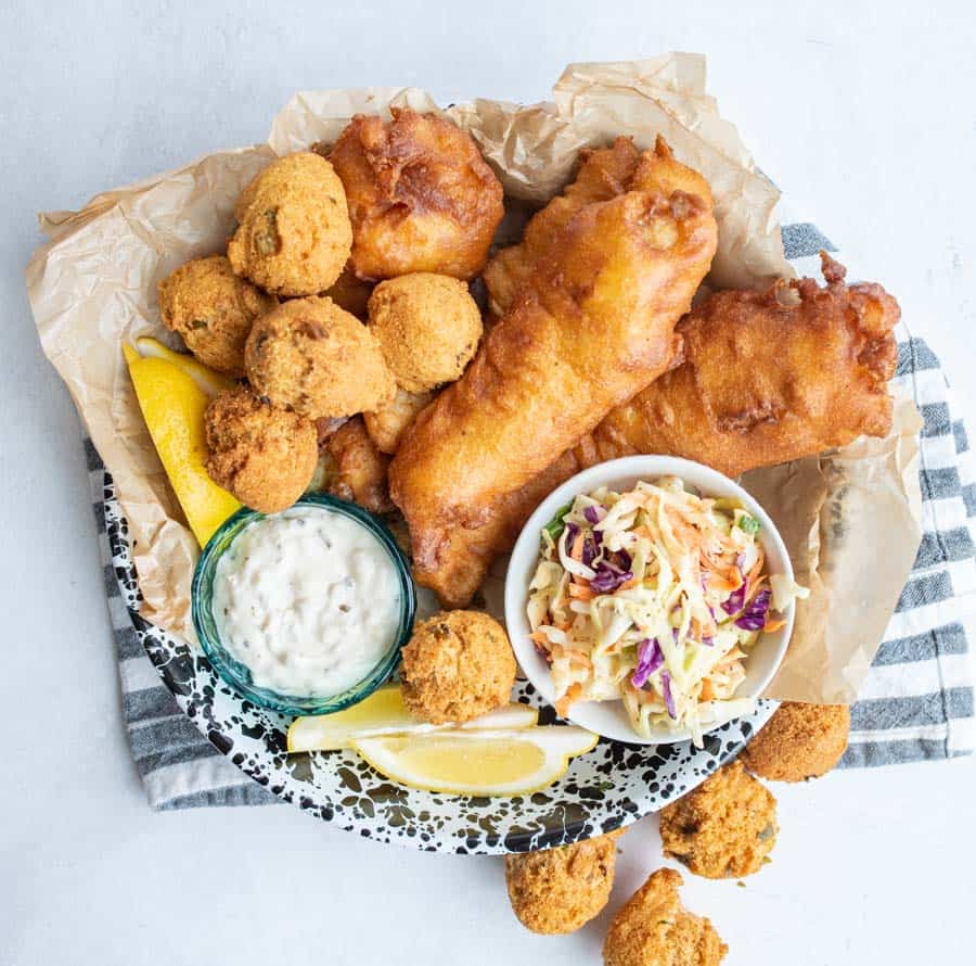 crispy deep fried and beer battered fish and hush puppies with tartan and lemons and coleslaw