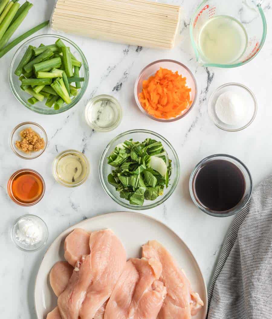 all raw ingredients for the chicken lo main in small clear dishes portioned and ready to make