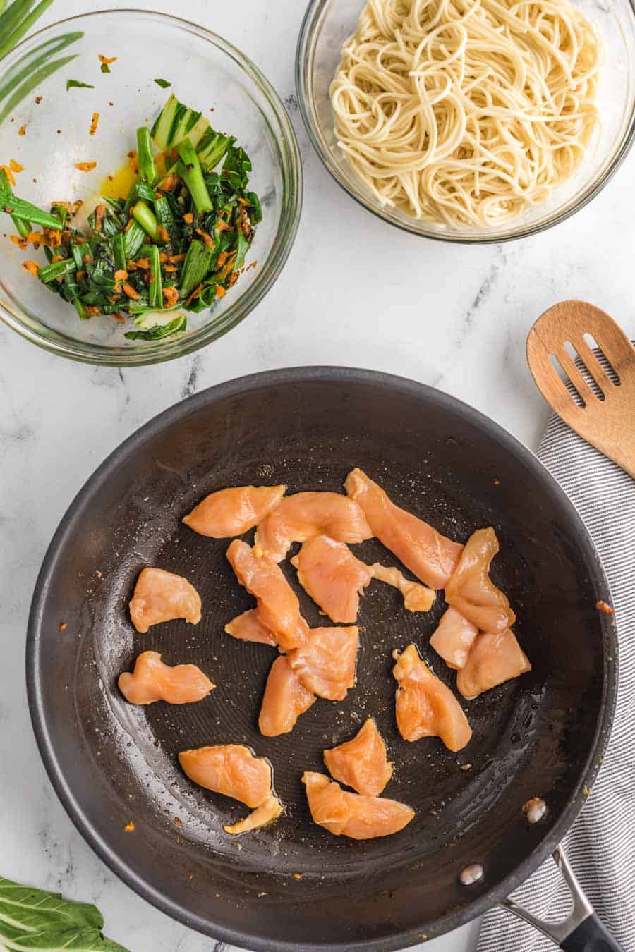 cooking raw chicken in a pan in preparation for the chicken lo main.