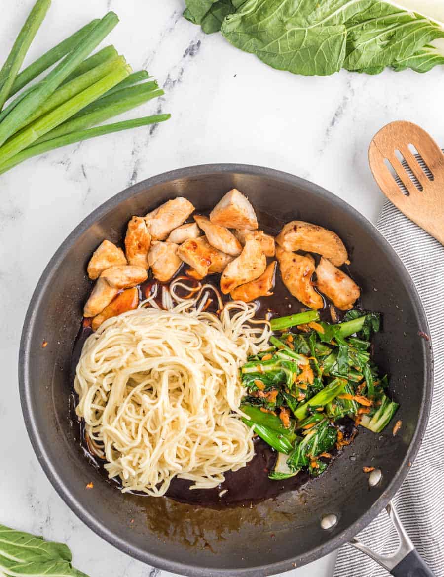 pan of chicken and sauce with lo main noodles and veggies not stored together yet.