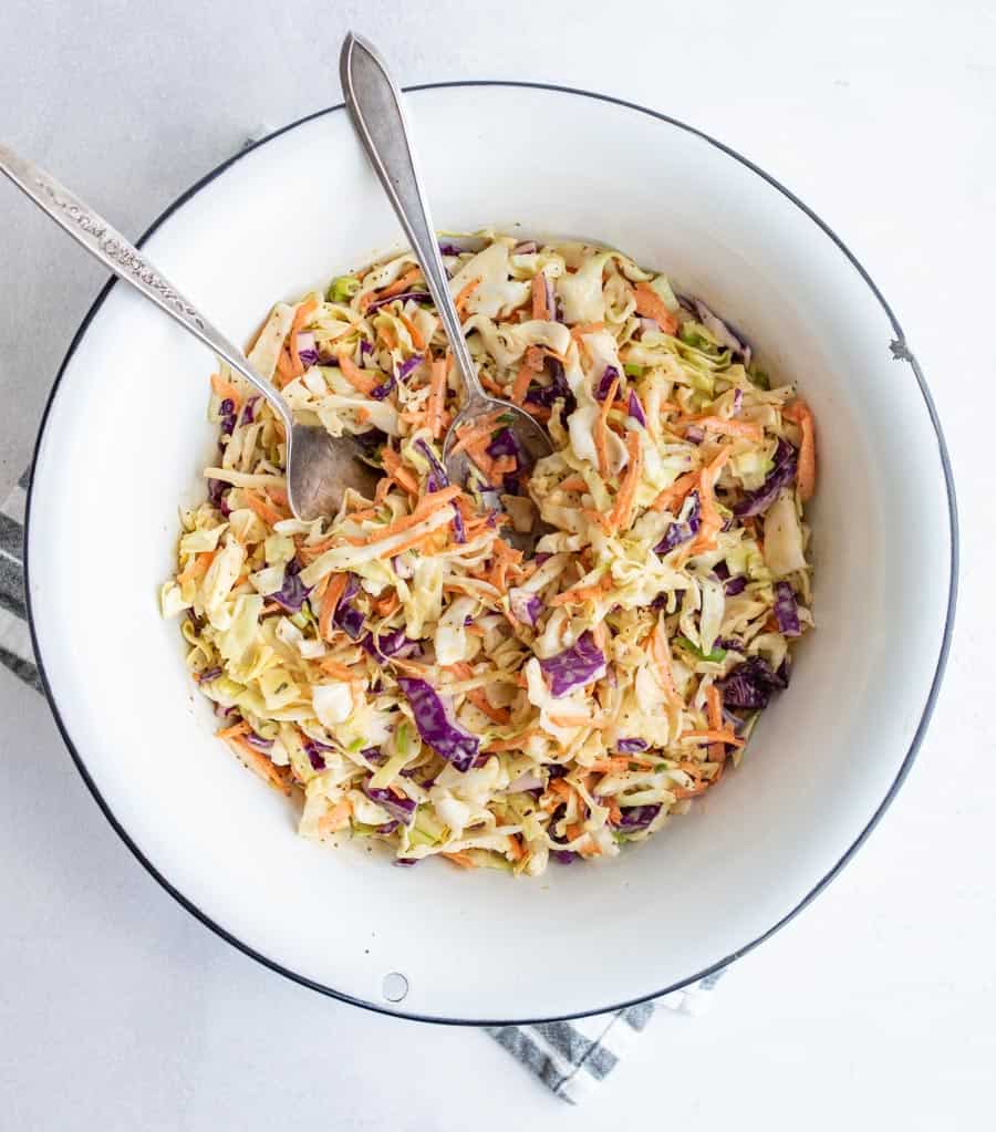 bowl of coleslaw that is dressed with cutlery