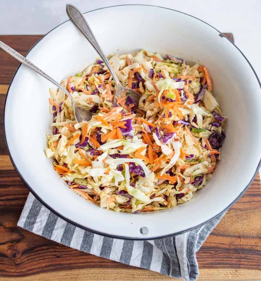 bowl of coleslaw that is dressed with cutlary
