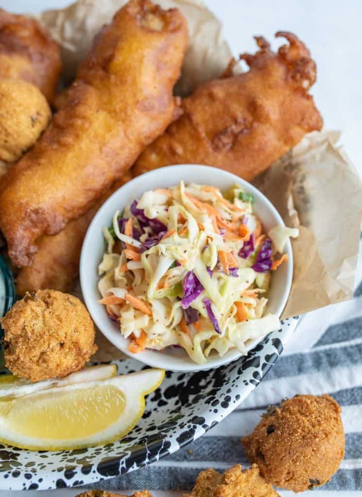 close up - crispy deep fried snacks and a lemon with a dish of coleslaw as the center