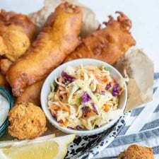 crispy deep fried snacks and a lemon with a dish of coleslaw as the center