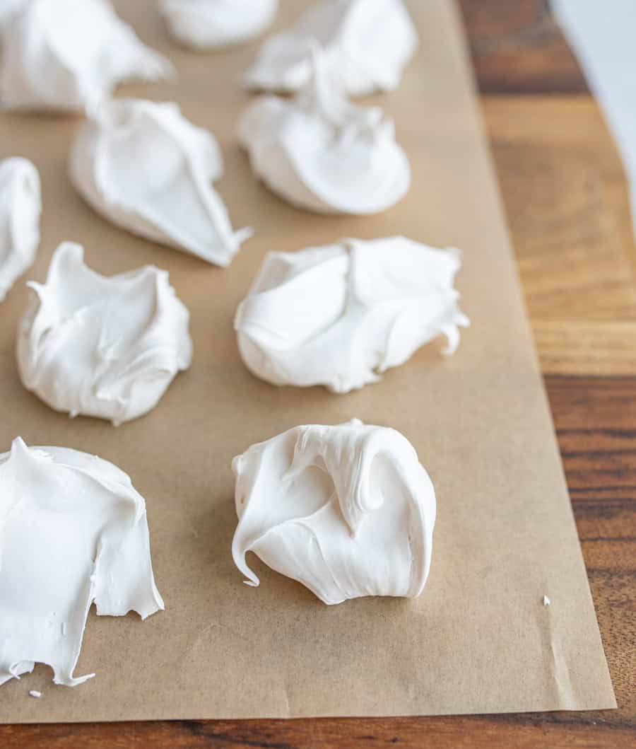 dollops of fluffy looking white divinity candy on parchment.