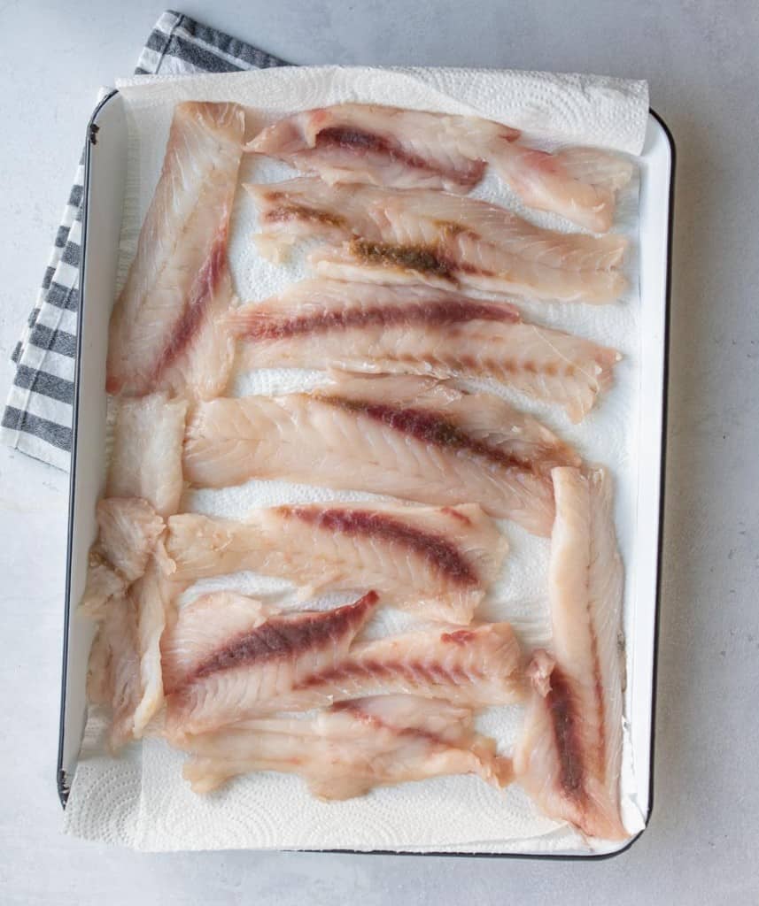 raw fish fillet drying on a baking sheet with a paper towel.
