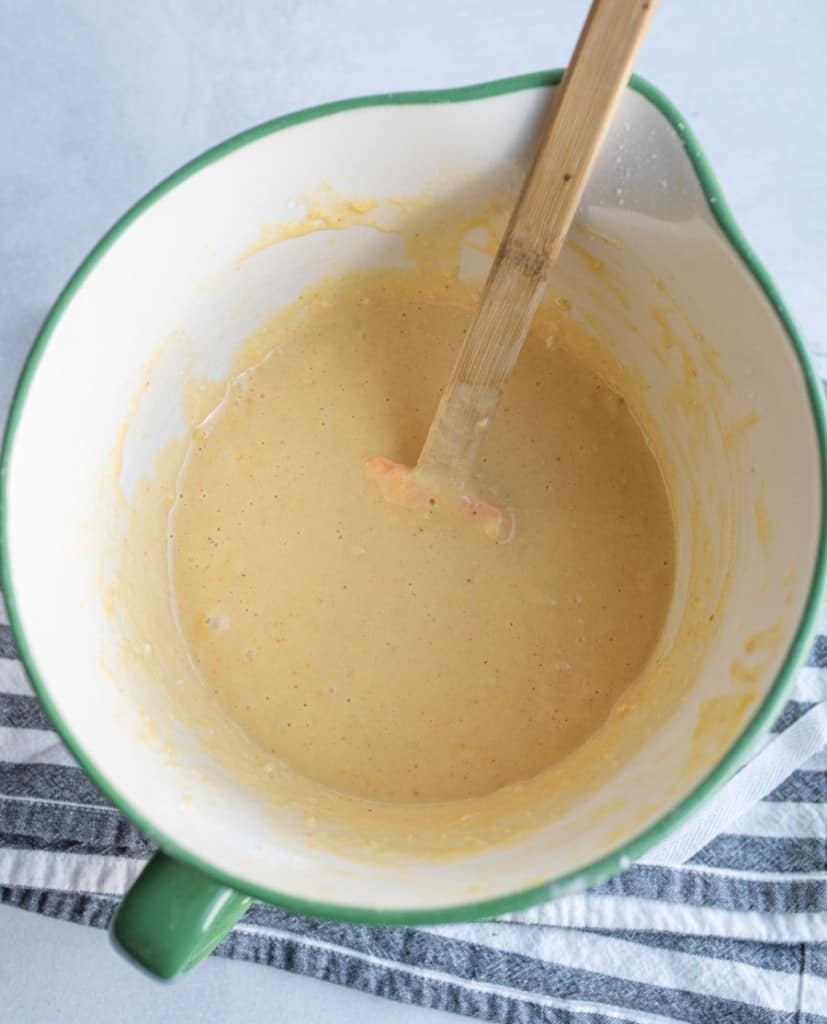 pourable mixing bowl with a wooden handled spatula mixing beer batter.