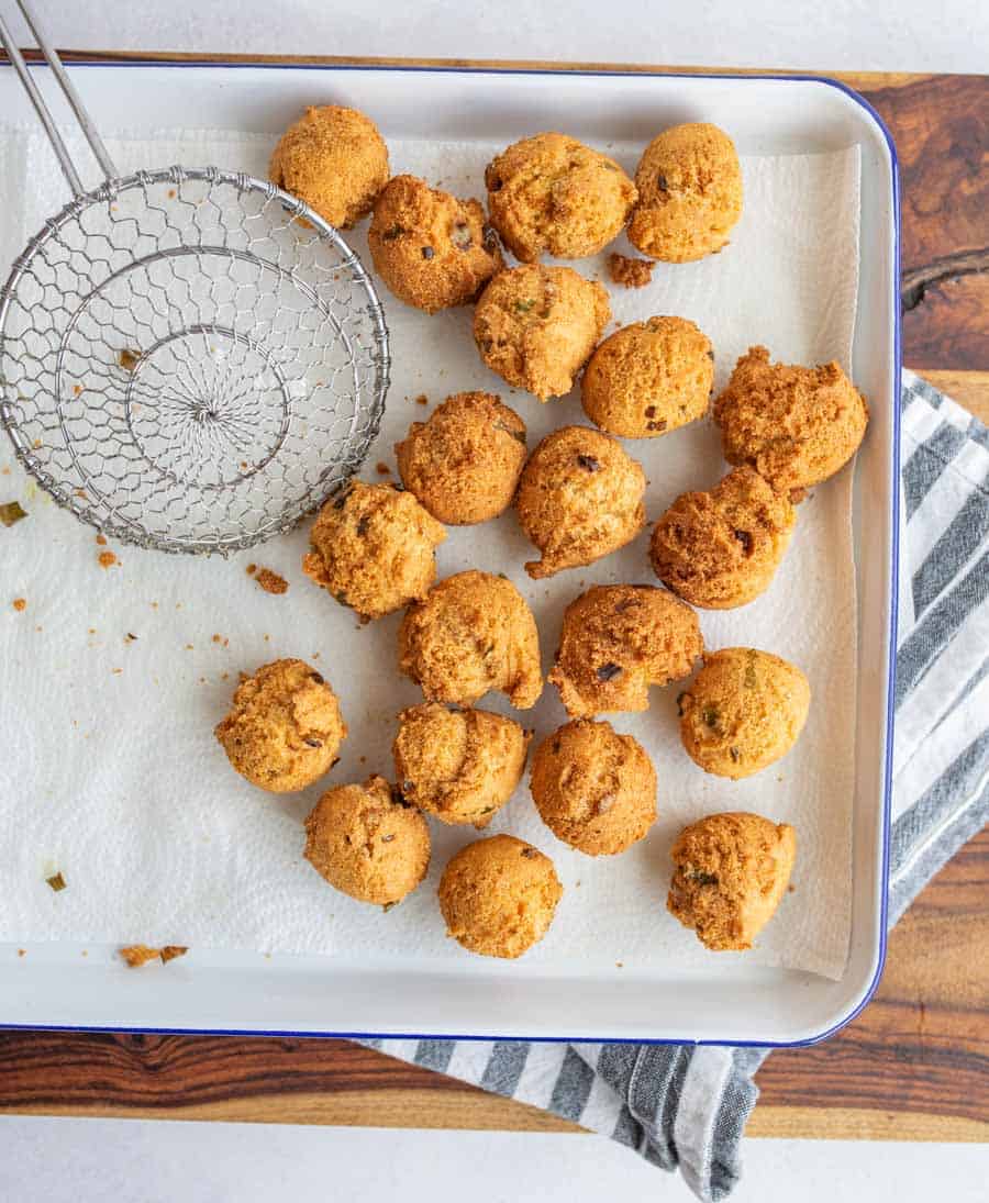 round balls of hush puppies fresh out of the fryer on a baking dish
