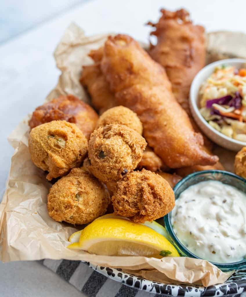 close up of the hush puppies with crispy fried beer batter fish in the background