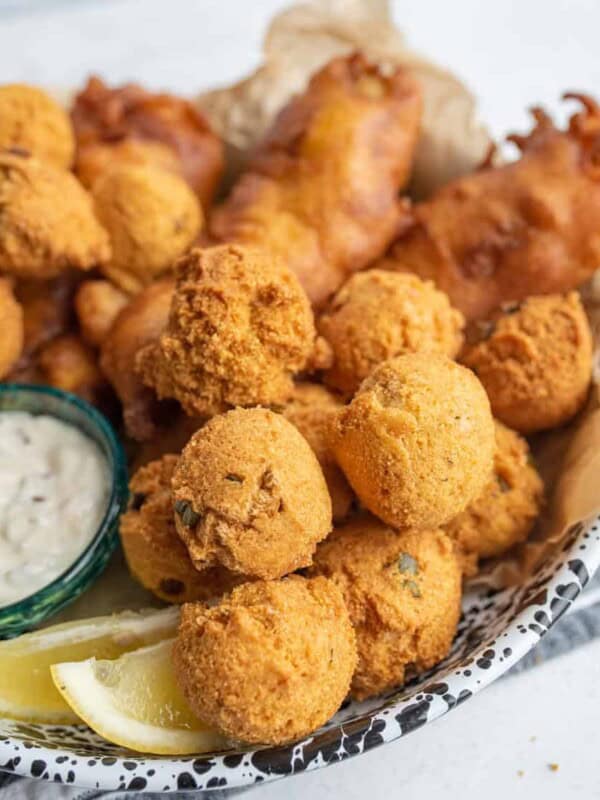 close up of the hush puppies with crispy fried beer batter fish in the background.