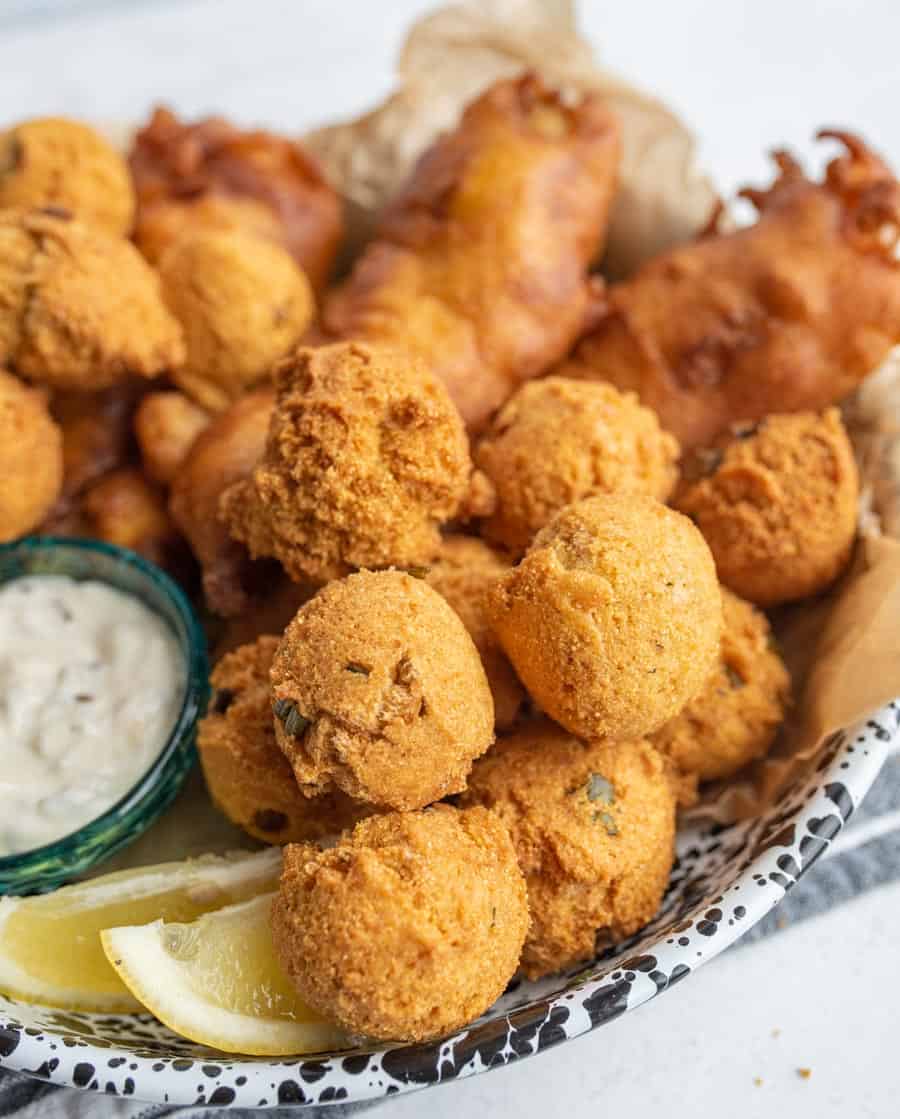 close up of the hush puppies with crispy fried beer batter fish in the background