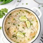 iron pot of rice with lime wedges and green onions garnished on top