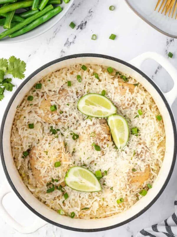 iron pot of rice with lime wedges and green onions garnished on top