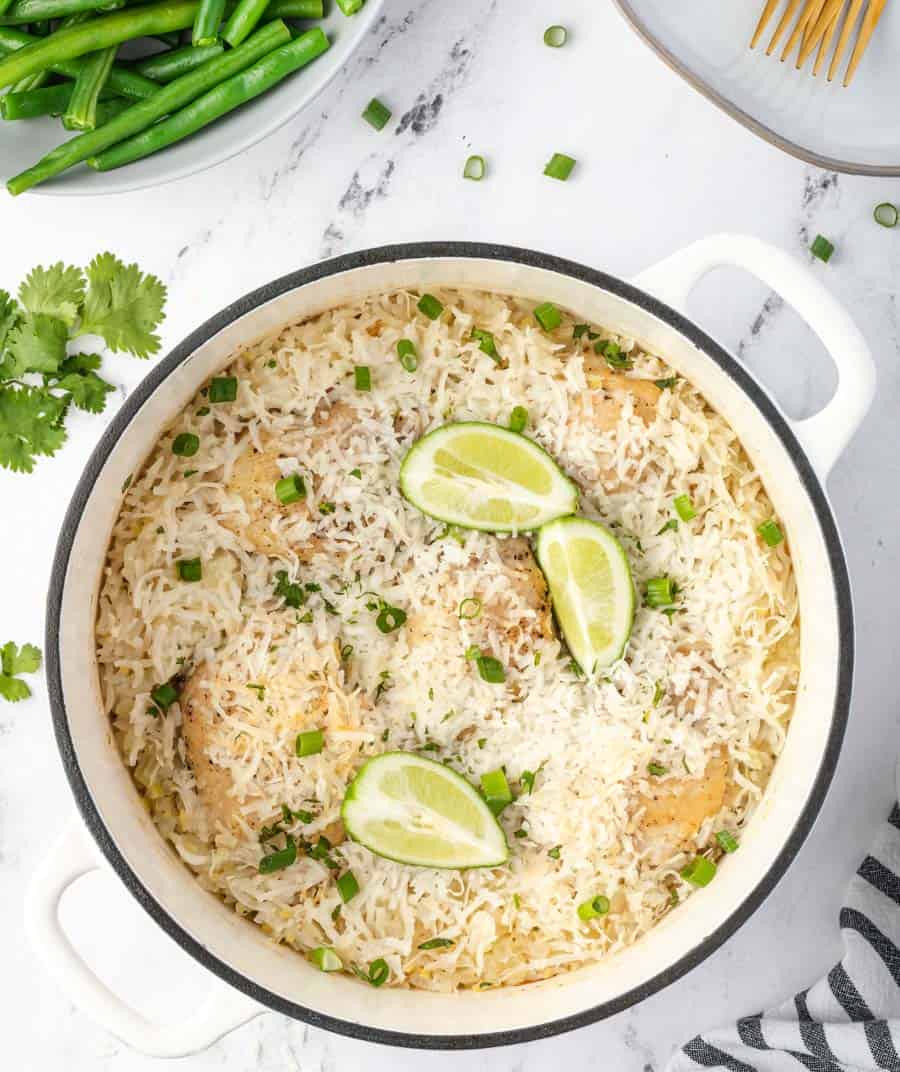 iron pot of rice with lime wedges and green onions garnished on top