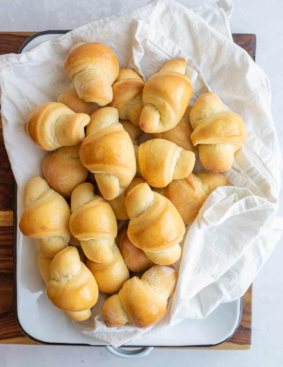 top view stack of small shiny buttered rolls in a rolled up croissant shape