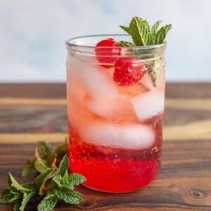 tumbler of a red "Shirley-Temple" drink with ice cherries and garnish