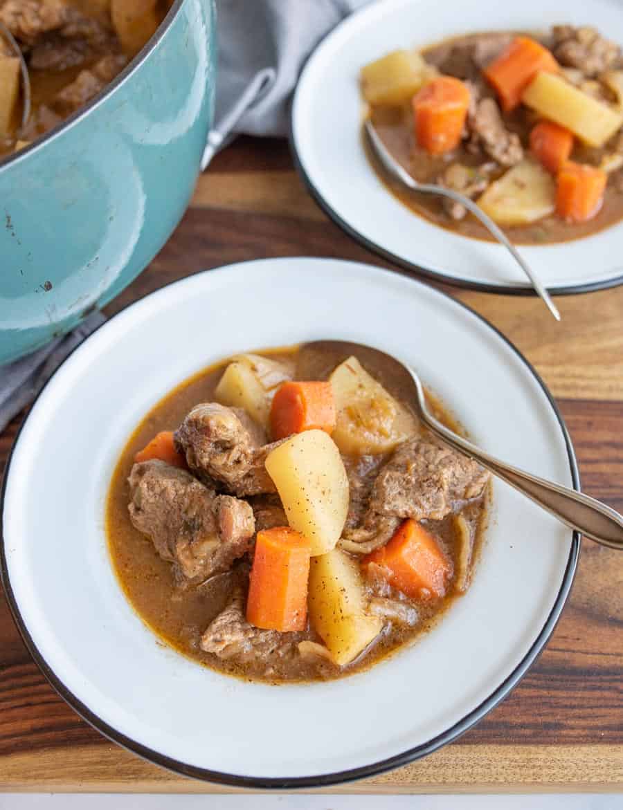 two bowls of hearty and traditional beef stew with a spoon