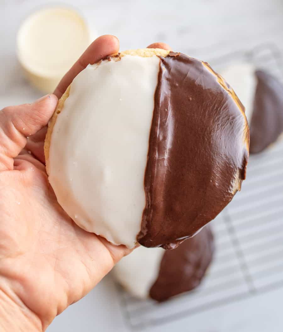 hand holding POV of one large black and white iced cookie exactly half and half split of each color