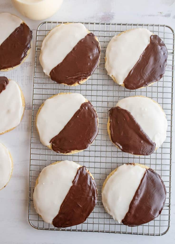 top view black and white iced cookies exactly half and half split of each color on a cooling rack