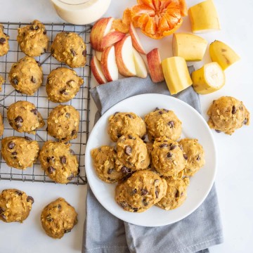 plate of breakfast cookies with some on a cooling rack with milk and fresh fruit all around