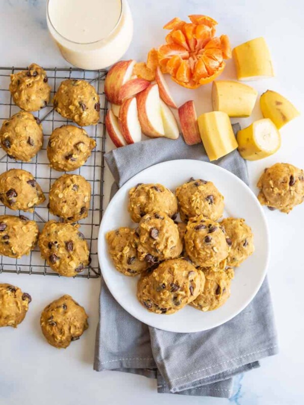 plate of breakfast cookies with some on a cooling rack with milk and fresh fruit all around